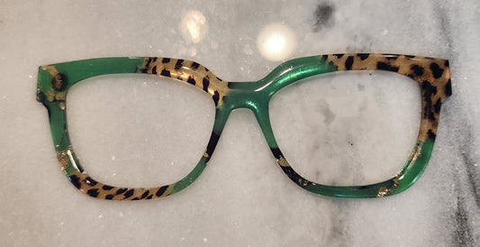 Green eyeglasses with leopard print temple tips on a gray marble surface