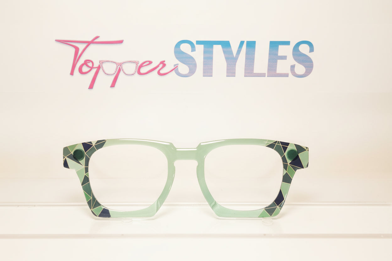 Green eyeglasses with geometric pattern on a white background, featuring the brand 'Topper Styles'.