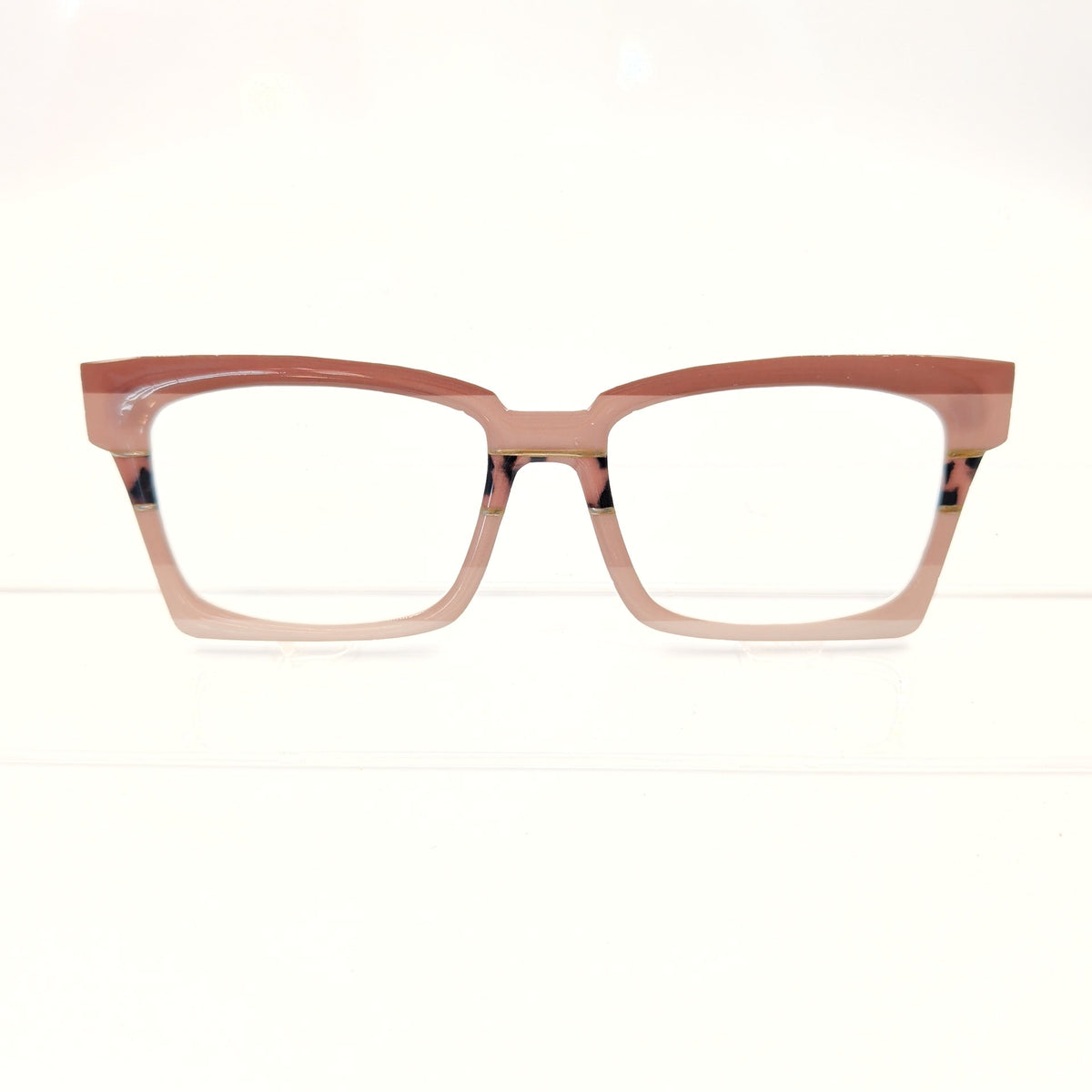 A pair of cat-eye style eyeglasses with a translucent dusty rose pink frame and clear lenses, displayed against a clean white background.